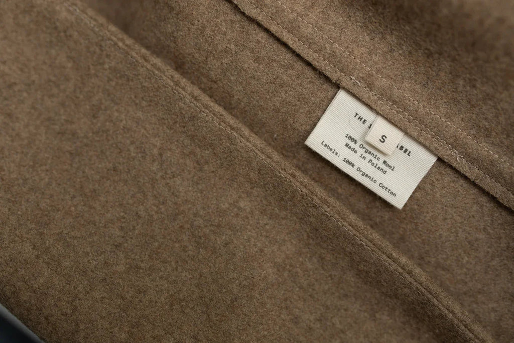 Close-up of a brown organic wool fabric with a clothing label showing size S and care information