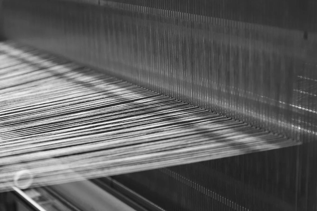 Close-up of threads on a wool fabric weaving loom in a textile manufacturing setting