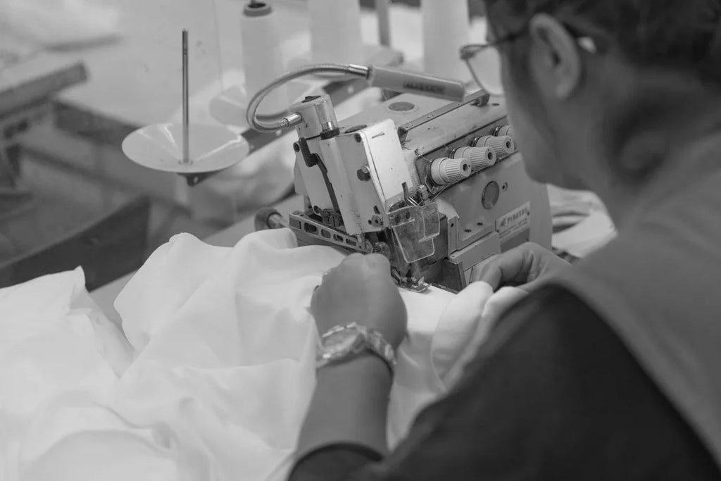 Tailor sewing white fabric using industrial sewing machine in textile factory