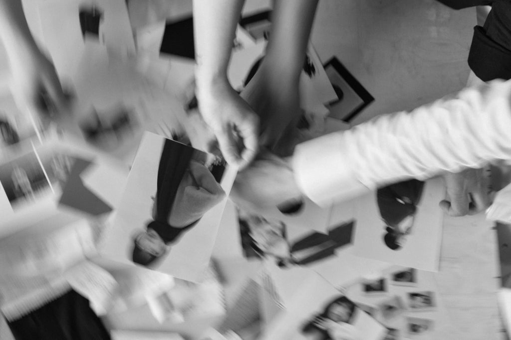 Black and white photo of hands sorting through fashion photos and magazine clippings on a table